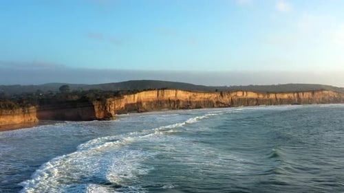 AERIAL Ocean Swells Roll Into Seaside Beach With Limestone Cliffs