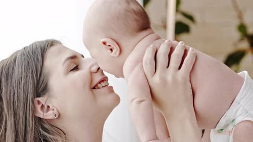 Mother Kissing and Lifting Baby in Air