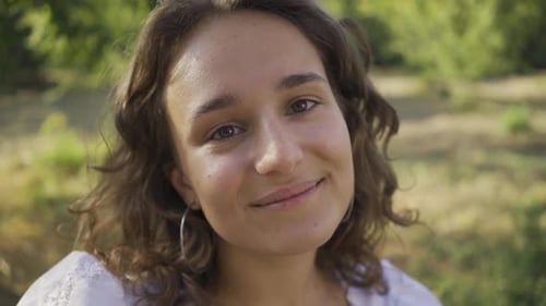 Portrait of Positive Young Woman with Curly Hair Looking at the Camera