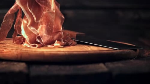 Ralenti, le jambon tranché en fines tranches tombe sur une planche à découper avec un couteau