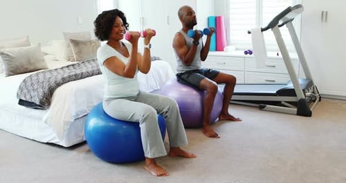 Couple Exercising with Dumbbells on Exercise Balls