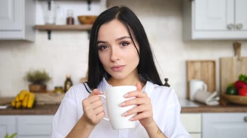 Woman Enjoying Coffee in a Bright Kitchen