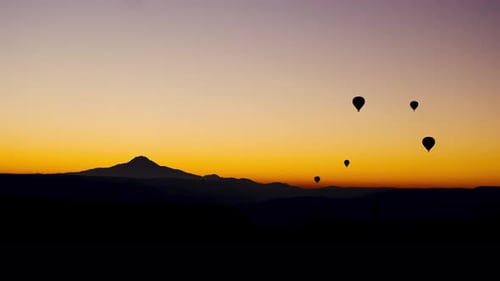 Hot Air Balloons Floating Over Mountain Range at Sunrise