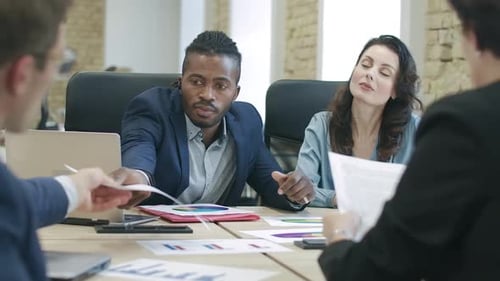 Group of Confident Multiethnic Colleagues or Partners Sitting in Office Examining Diagrams