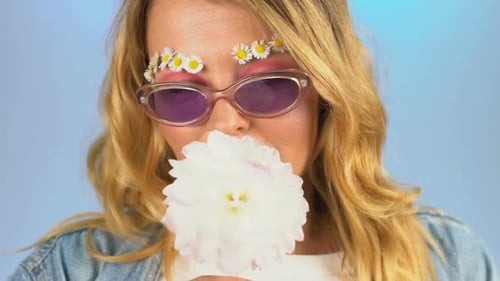 Woman Smelling Flower With Daisy Eyebrows and Sunglasses