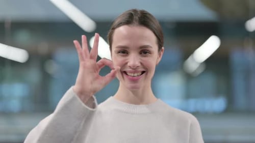 Young Woman Gives OK Hand Gesture and Smiles