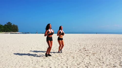 Young smiling ladies on holiday having fun at the beach on summer white sand and blue 4K background