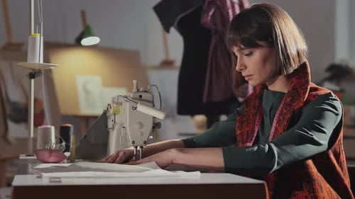 Young Girl In Sewing Studio Sews Behind Sewing Machine