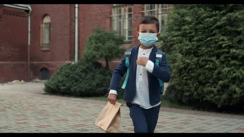 Young Boy Walking with Mask Outside School Building