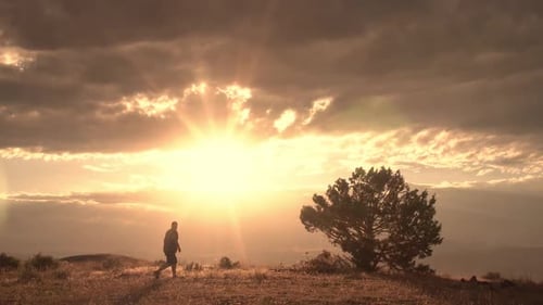 Man walking on hilltop raising arms with joy
