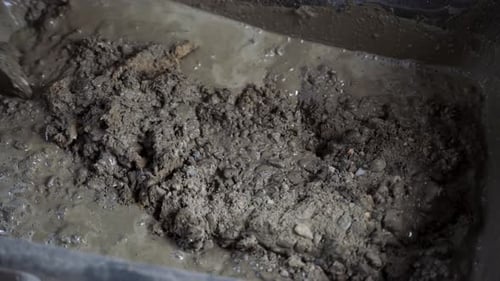 Mixing Cement in Gray Container with Metal Tool