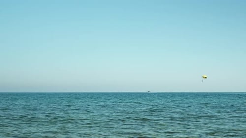 Yellow parachute flying over sea water surface.
