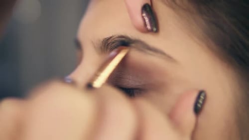 Augenbrauenpflege beim professionellen Schminken Nahaufnahme einer jungen Frau, die ihre Brauen mit der Braue in Form bringt