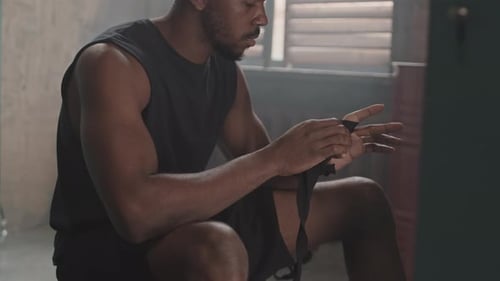 Boxeador masculino vendando las manos antes del entrenamiento