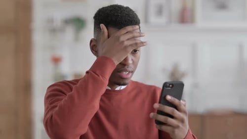 Young Adult Reacting to Shocking News on Smartphone