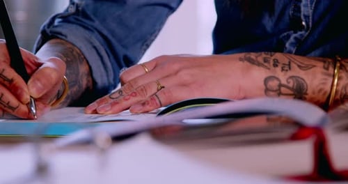 Close-up of tattooed hands working on fashion design