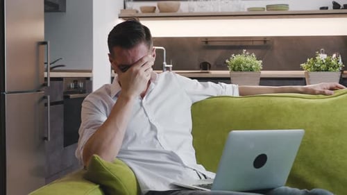 Stressed Man Using Laptop While Sitting on Couch