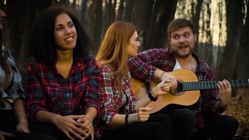 Happy Tourists Singing Songs with Guitar in Autumn Forest