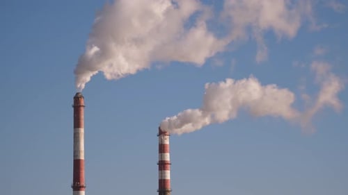 Industrial Smokestacks Releasing Thick Smoke Against Blue Sky
