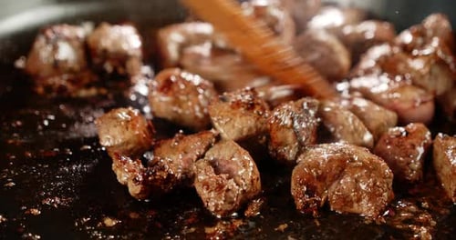 A Wooden Spatula Stirs the Fried Liver in Oil.