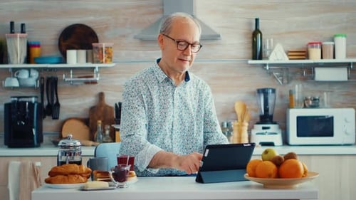 Senior Man Using Tablet at Kitchen Counter