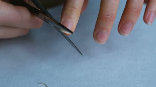 Woman is Making Herself a Manicure with Scissors Closeup