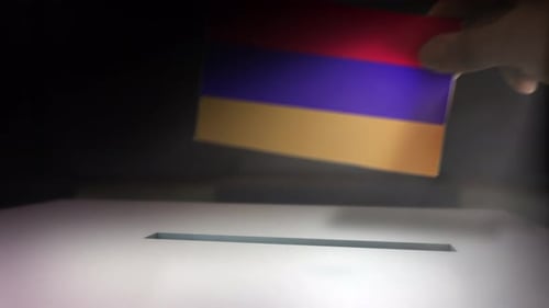 Hand Placing Armenian Flag into Ballot Box