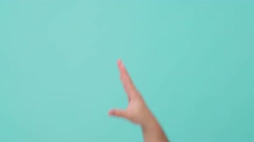 Close up shot of human hand raising stretch out hand flicking off in isolate blue screen background.