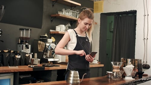 Young Woman Smiling at Phone in Coffee Shop