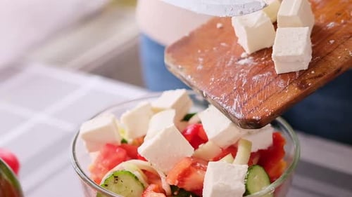 Concept de la série de préparation de salade grecque femme versant du fromage feta tranché dans un bol