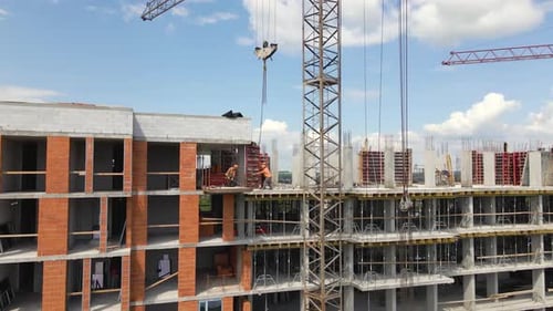 Tower Cranes and Professional Workers at High Concrete Residential Building Under Construction