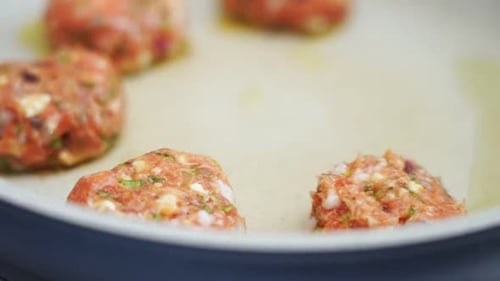 Unrecognizable person cooking meatballs on frying pan with oil