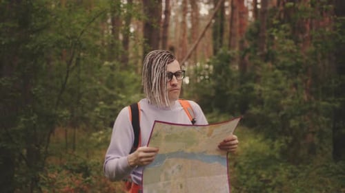 Traveling Man with Dreadlocks with Map in Woods