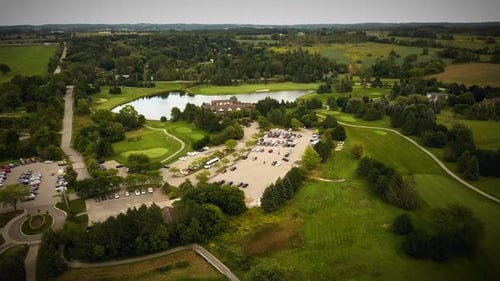 Drone flying over a beautiful golf course surrounded by vast fields.