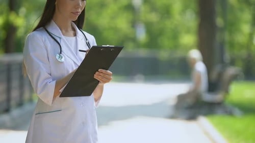Medical Worker Filling Medical Data in Park, Woman Smoking on Background