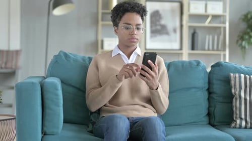 Woman Using Smartphone on Sofa Indoors