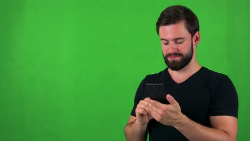 Young Handsome Bearded Man Works (Typing) on Smartphone - Green Screen - Studio