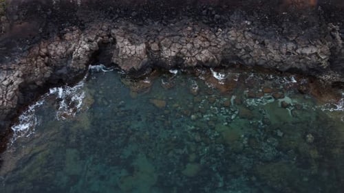 Vista aérea de arriba hacia abajo vista de pájaro de una costa rocosa con agua de mar tranquila