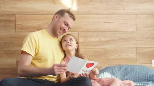 Loving Father Reading Birthday Card with Daughter