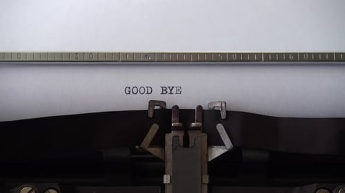 Typing phrase GOOD BYE on retro typewriter. Close up.