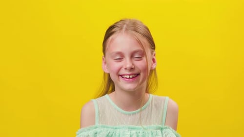 Kleines Mädchen blickt mit einer Haarsträhne im Gesicht in die Kamera und lächelt mit ihren Zähnen