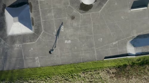 Aerial drone view of a skater practicing flips at a skate park.