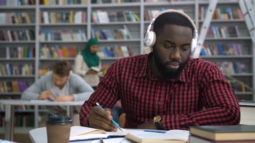 Dunkelhäutige Studentin studiert mit Buch in Bibliothek