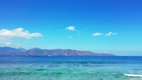 Tranquil sea scene with white waves splashing on coral reef barrier, blending with calm clear turquo