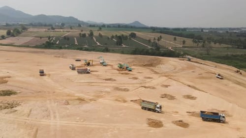 Antenne von mit Sand beladenen Lastwagen auf der Baustelle, Bagger, die den Boden graben, Luftumkreisen