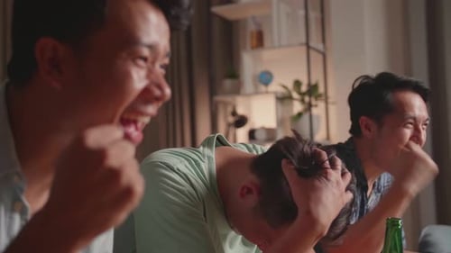 Three Asian Males Cheering And Watching Football Game On Tv