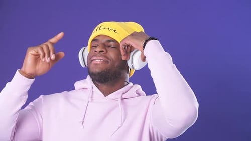 Man Listens to Music with Headphones on Purple Background