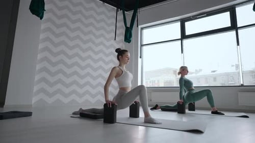 Group of Young Women Stretching in Gym with Windows