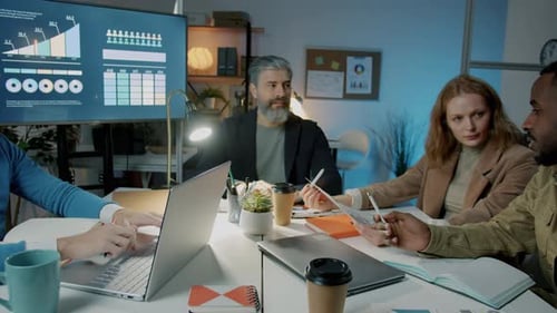 Zoomin of Businessman Speaking to Colleagues Diverse Team During Meeting in Office at Night