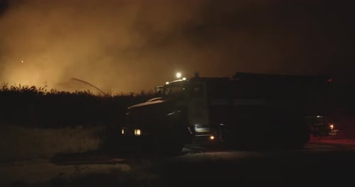 Fire Truck with Flashing Lights On. Fire Truck on Background of Burning Grass on Field During Forest